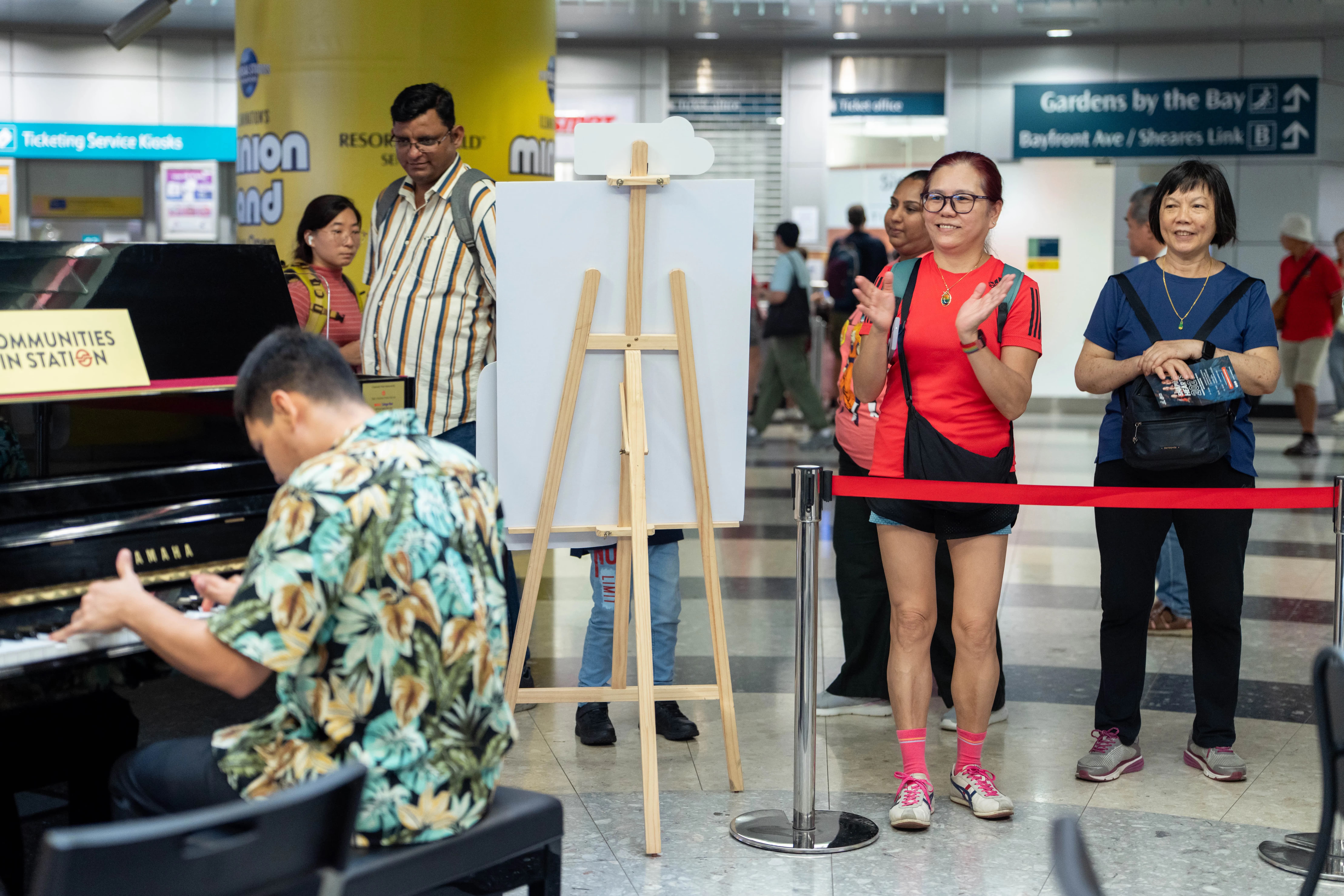 Audience applauding a person with disabilities performing live on a piano.